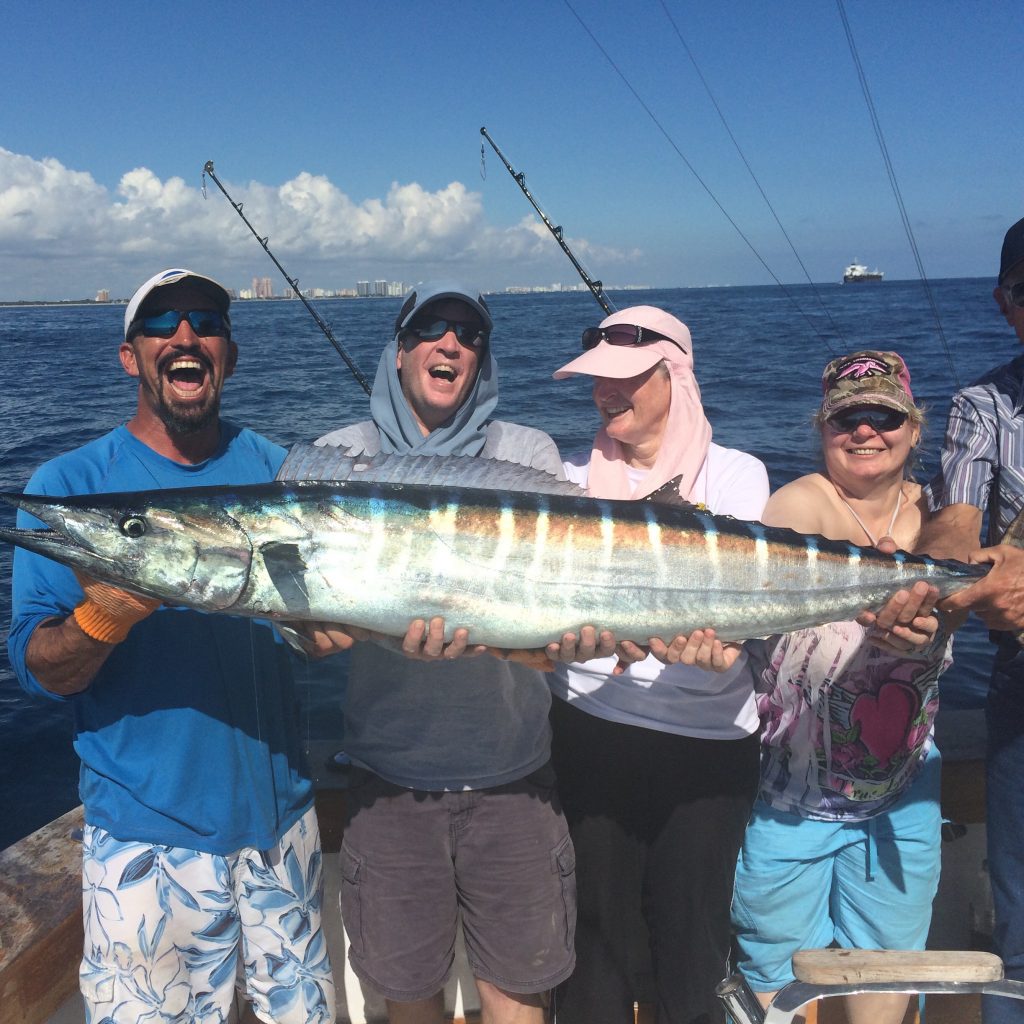 A group holding a big wahoo just caught on their private fishing charter.