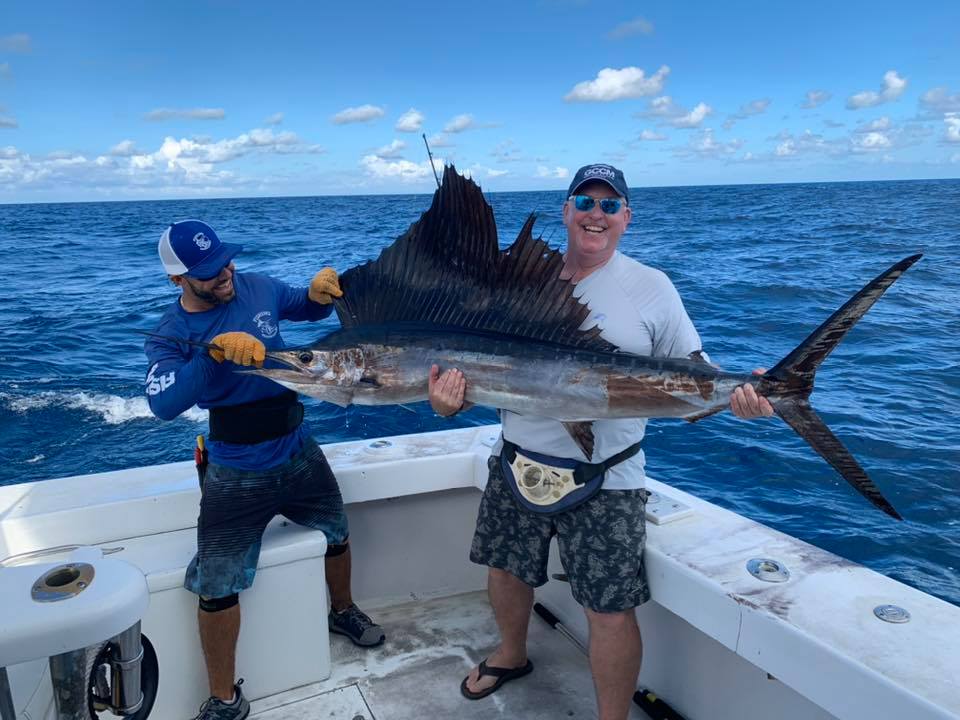 Happy angler holding a sailfish that was just caught off the coast of Fort Lauderdale.  Beautiful sky in the background.